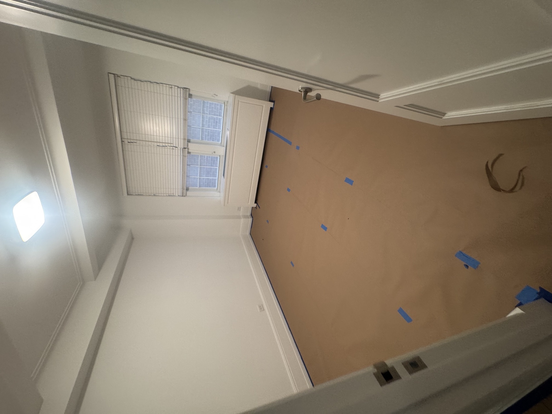 Room masked with kraft paper and blue tape, fresh trim ready for paint