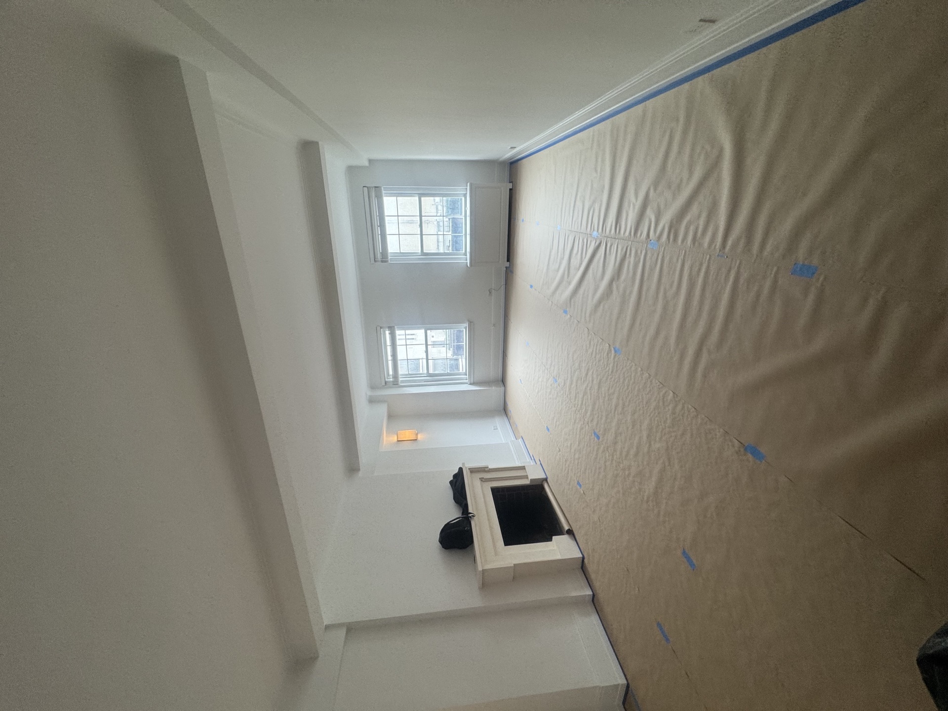 Hallway masked for painting with kraft paper and white-trimmed fireplace surround