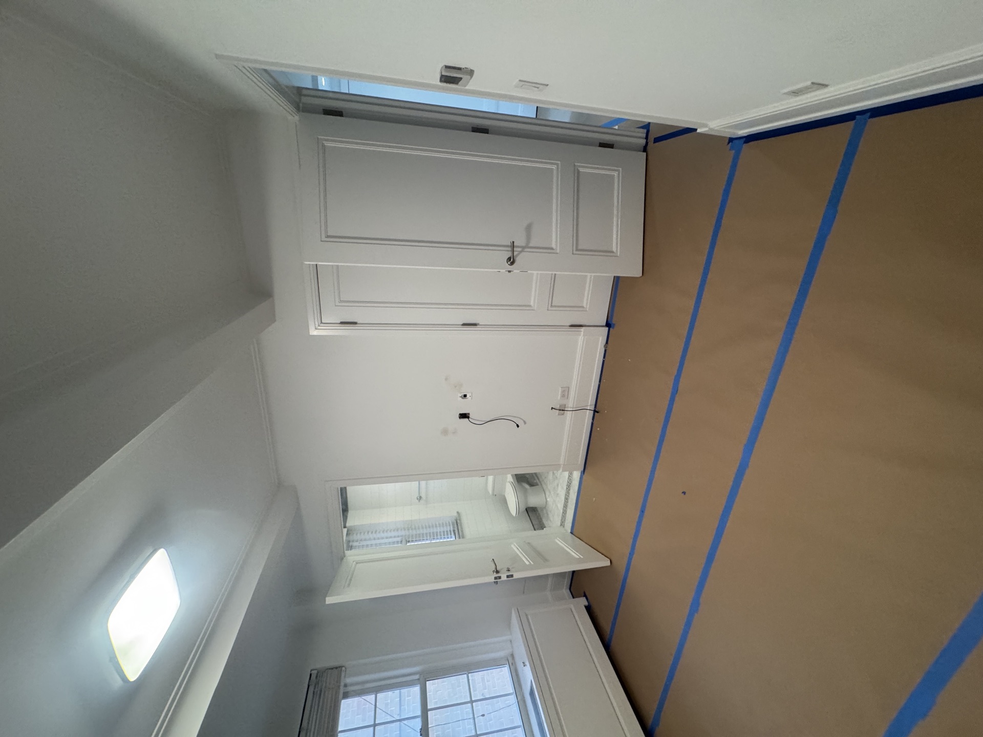 Painted interior with white upper cabinetry and kraft paper masking
