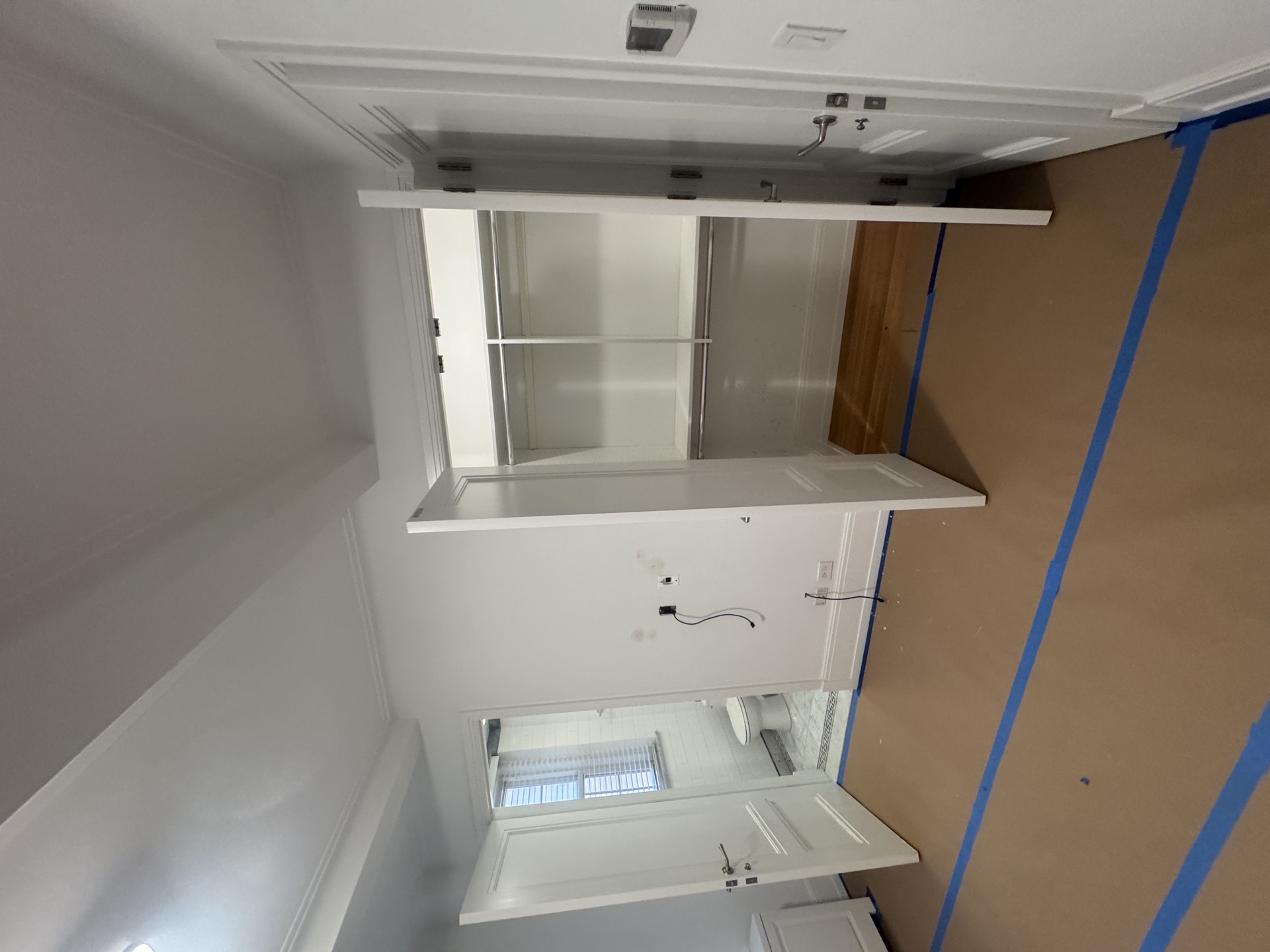 Freshly painted built-in shelving nook with protective paper on surrounding walls