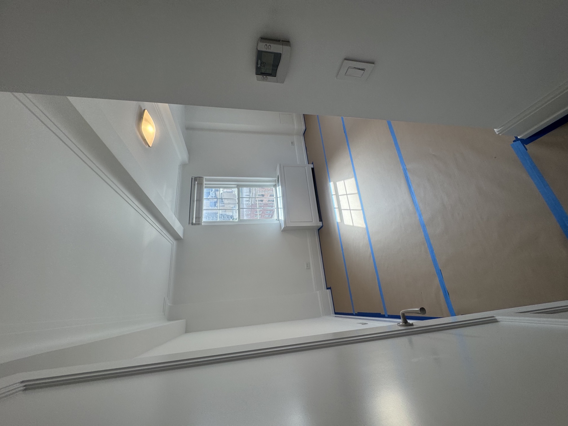 Painted stairwell landing with sconce, window, and masked walls