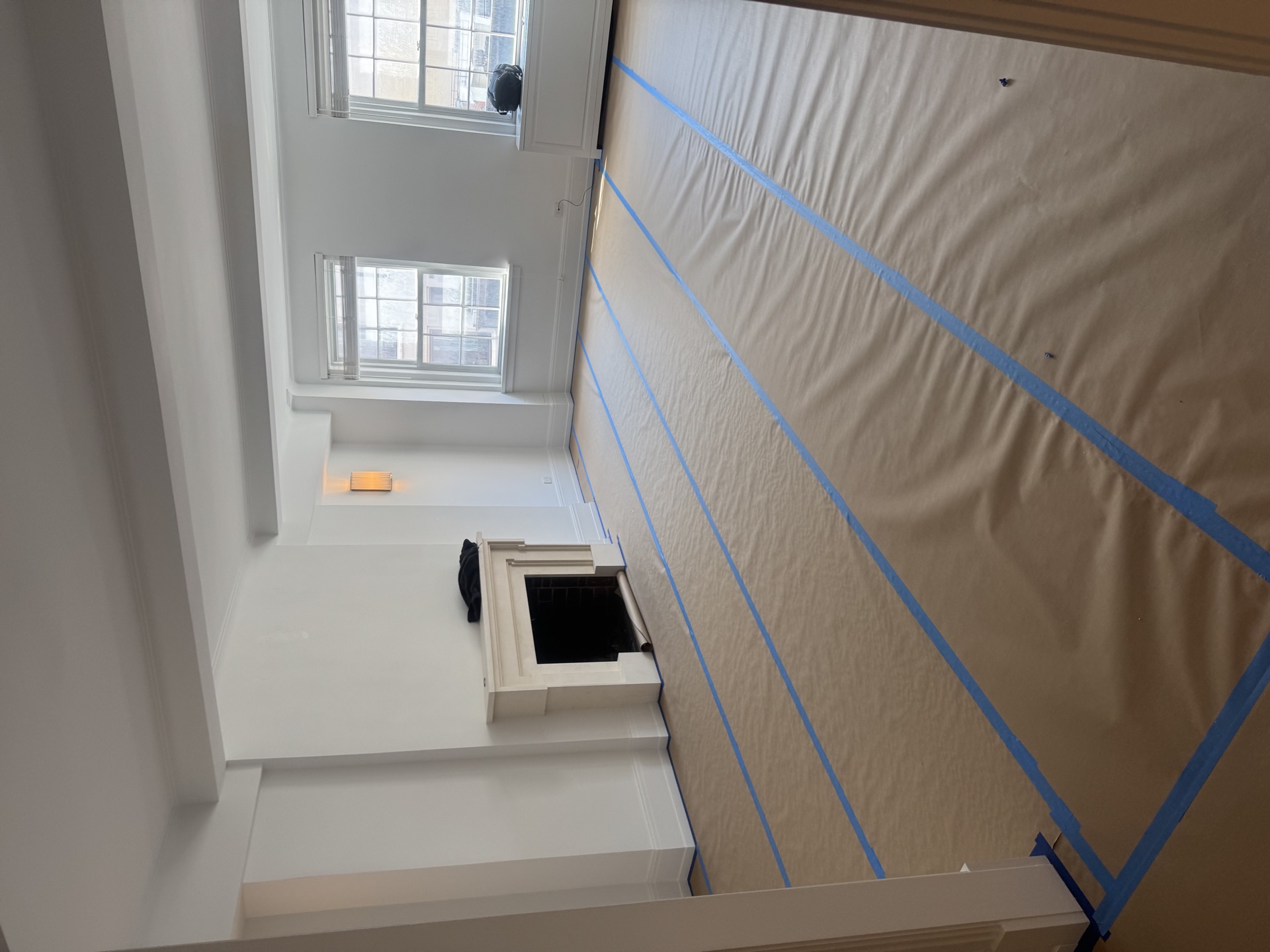 Stair landing with tall windows, crown molding, and masked walls