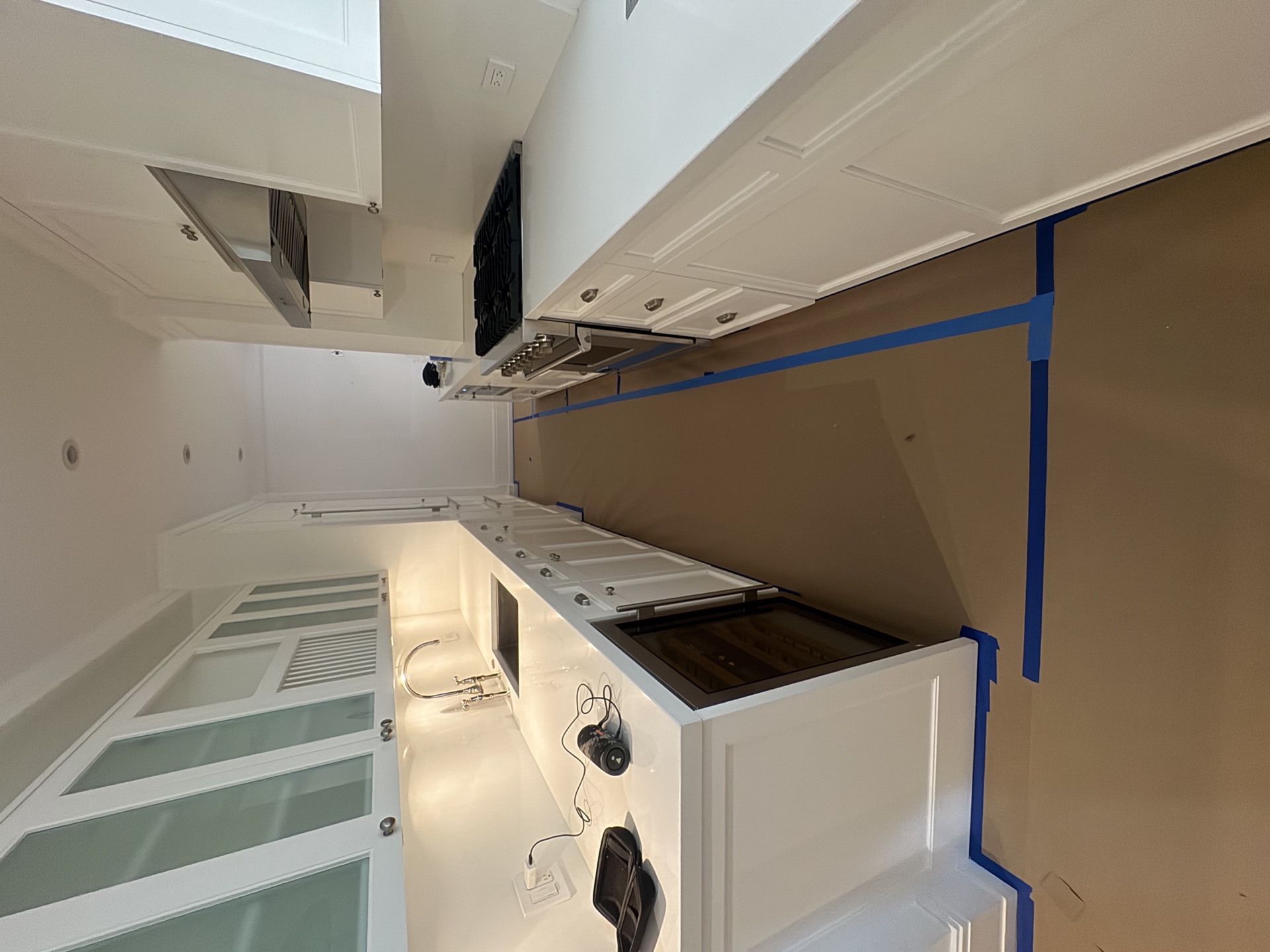White kitchen with pro gas range, custom cabinetry, quartz counters, and glass-front uppers