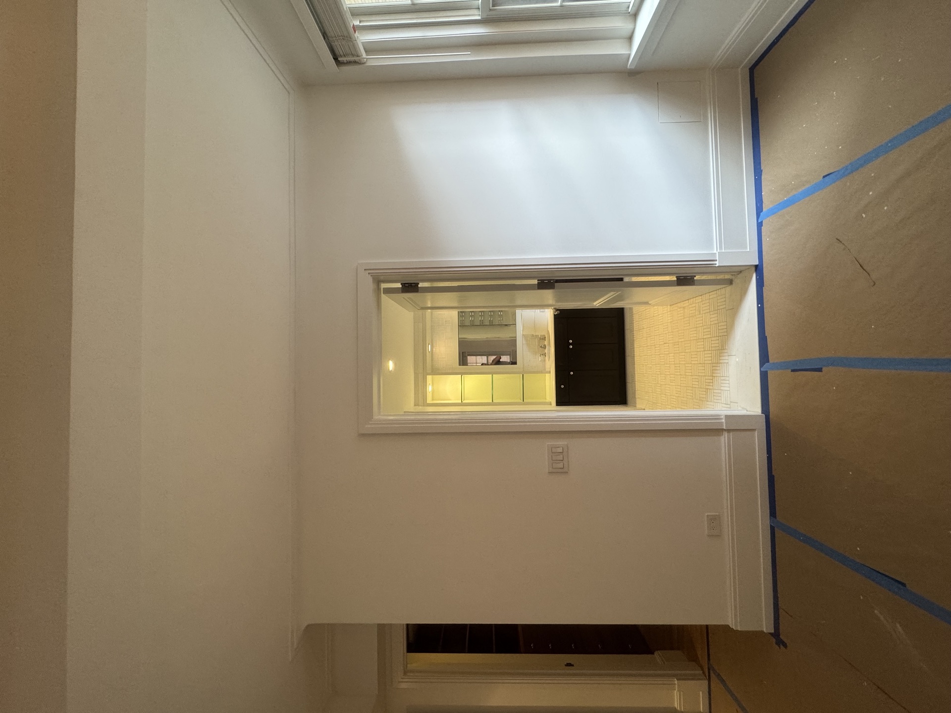 Interior landing looking through to a bathroom, walls masked with protective paper