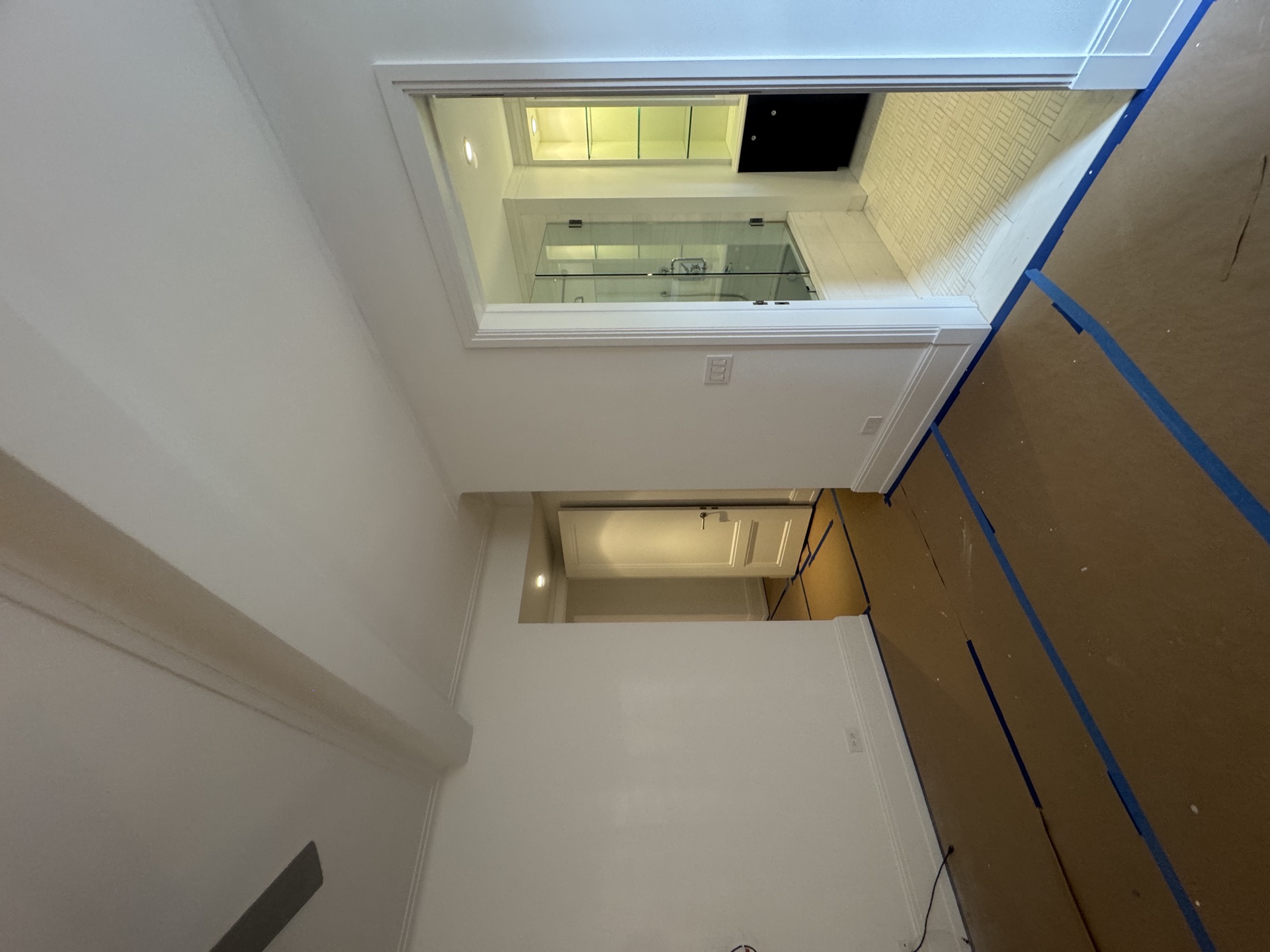 Hallway view toward a finished bathroom with glass shower enclosure