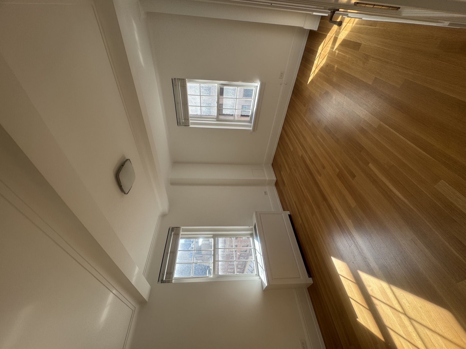 Bright bedroom with newly laid hardwood floors and double windows