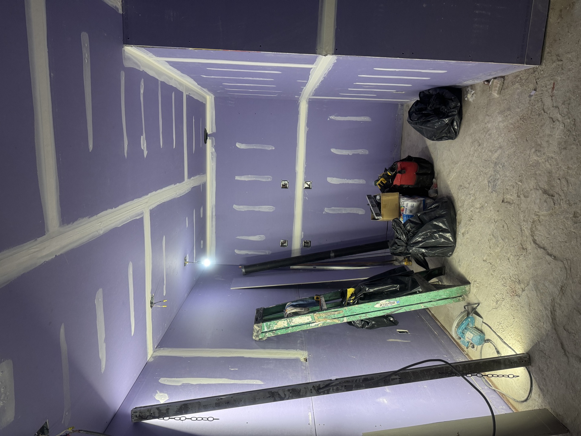 Room with purple moisture-resistant drywall taped and mudded