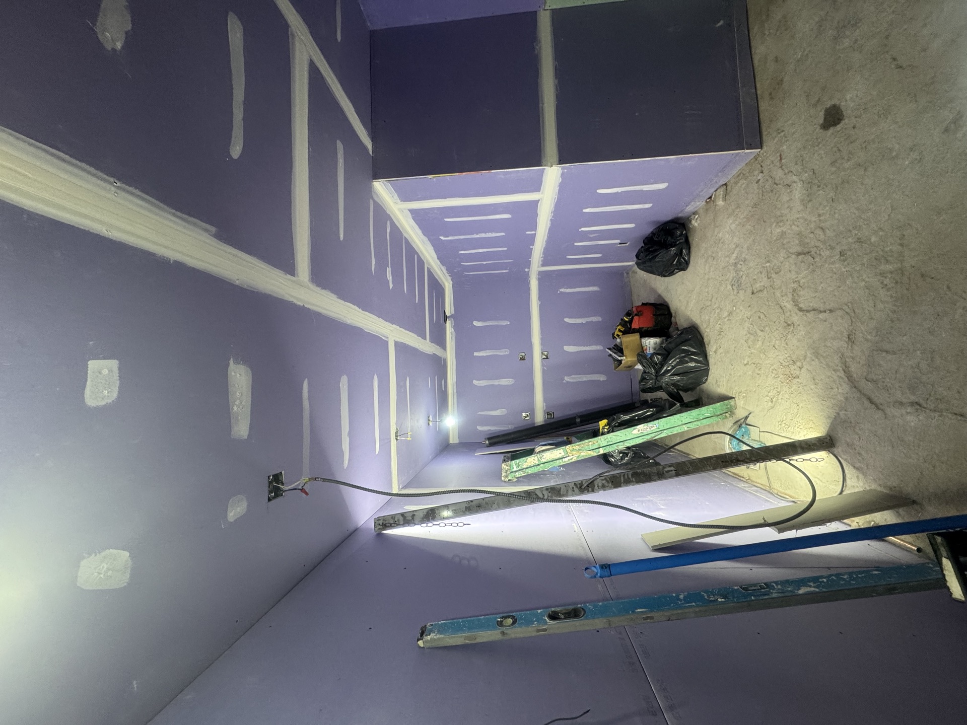 Drywall hanging and taping in progress with purple board and joint compound