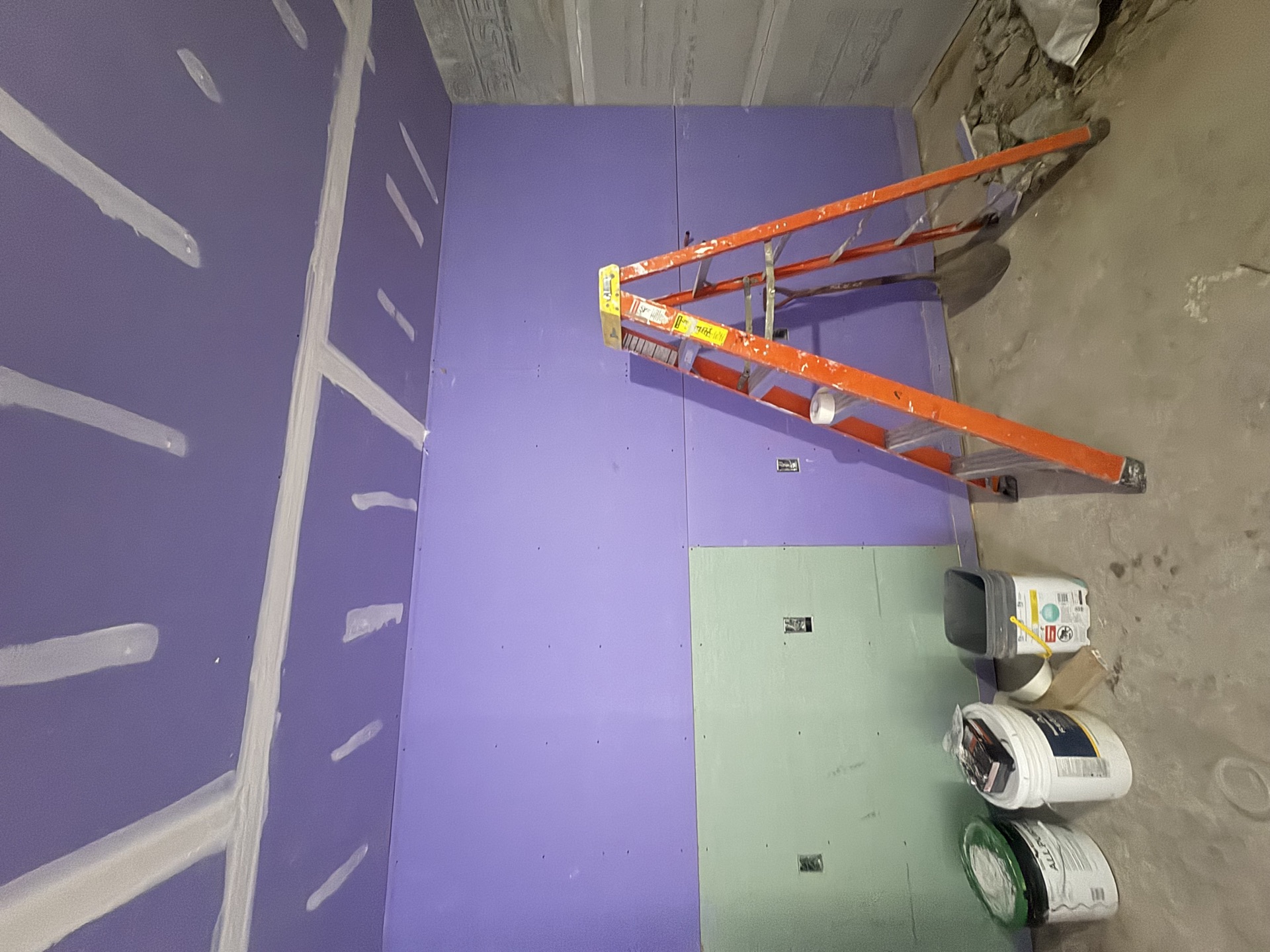 Taped drywall with ladder and joint compound buckets during paint prep