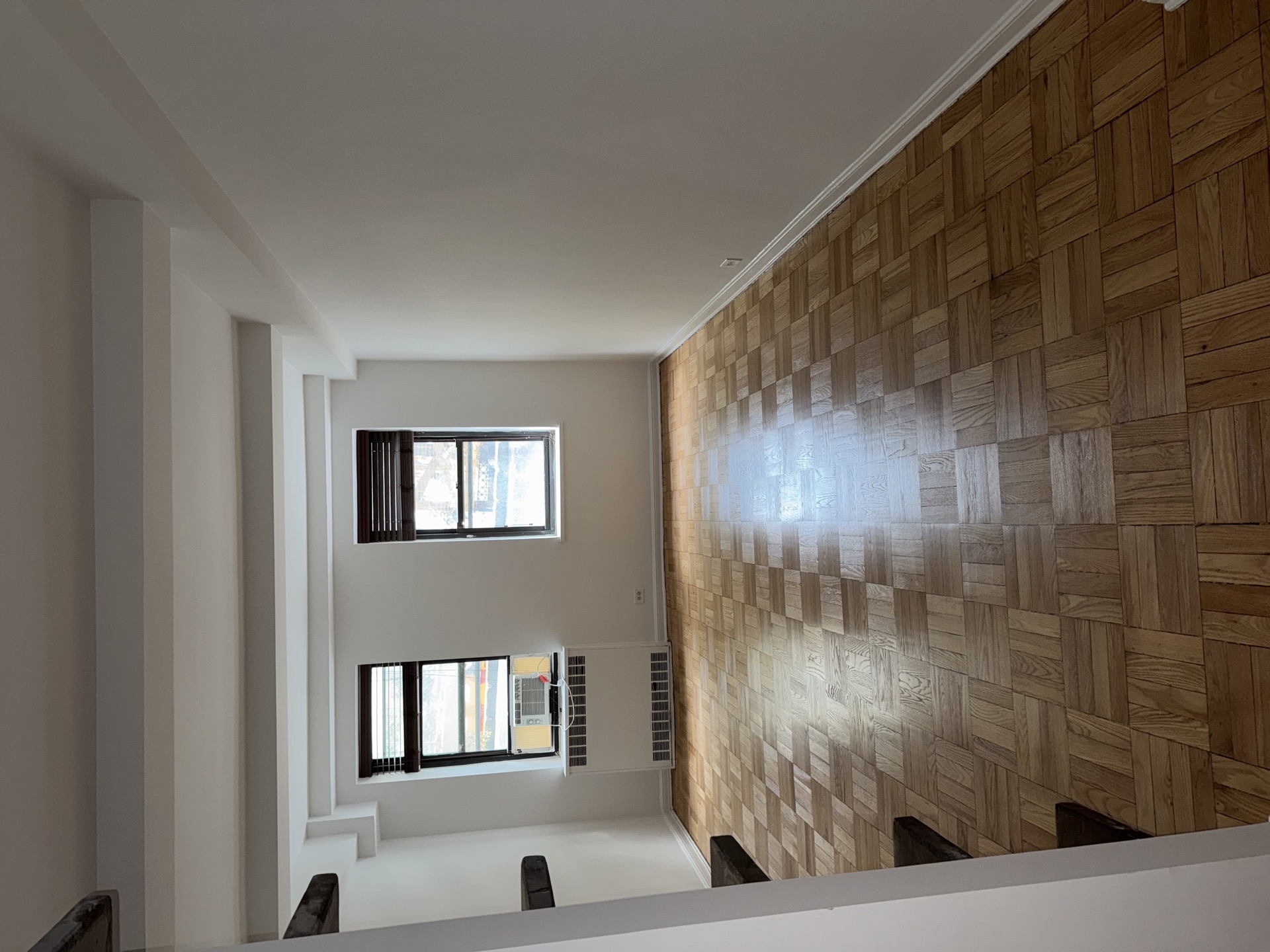 Parquet accent wall and matching hardwood floor in a sunlit room
